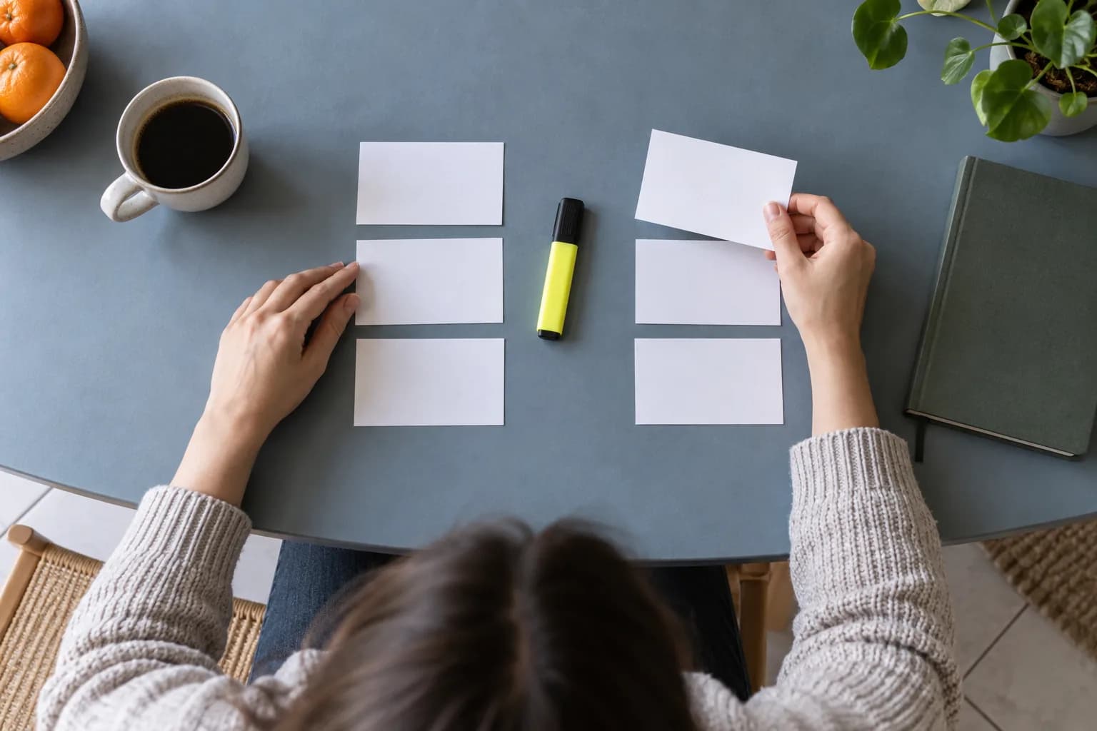Hands arranging blank cards into job needs and evidence on a blue-gray table
