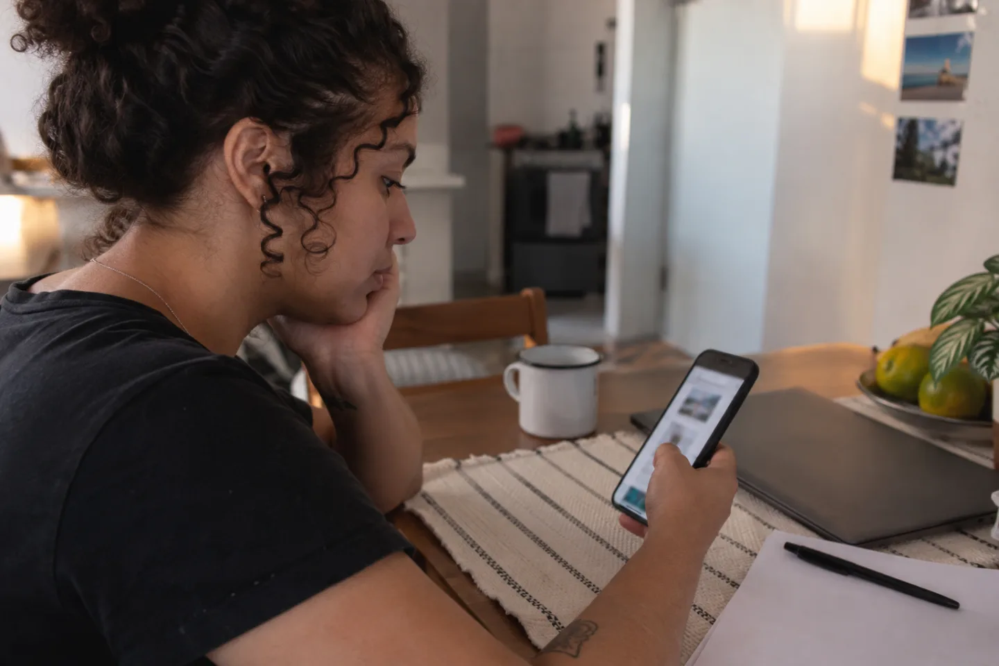Applicant checking a blurred portfolio page on a phone beside blank application papers