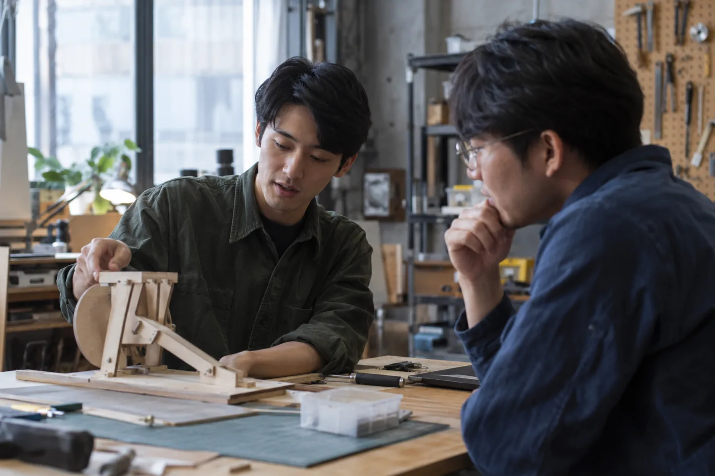 Two young adults discussing a wooden prototype in a community workshop