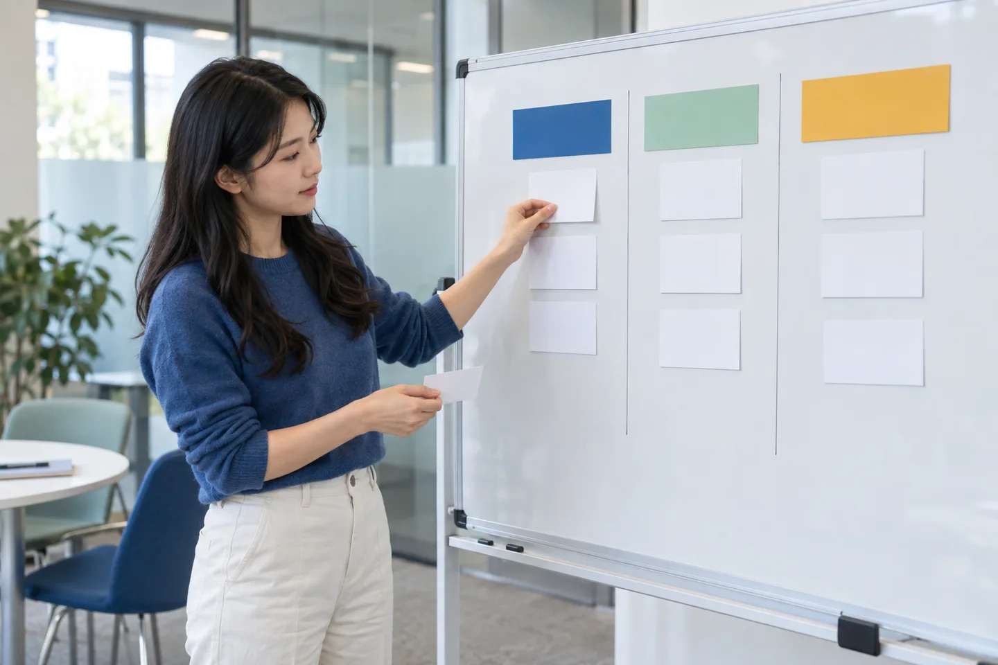 Young professional sorting blank cards across three columns on a whiteboard in a career center